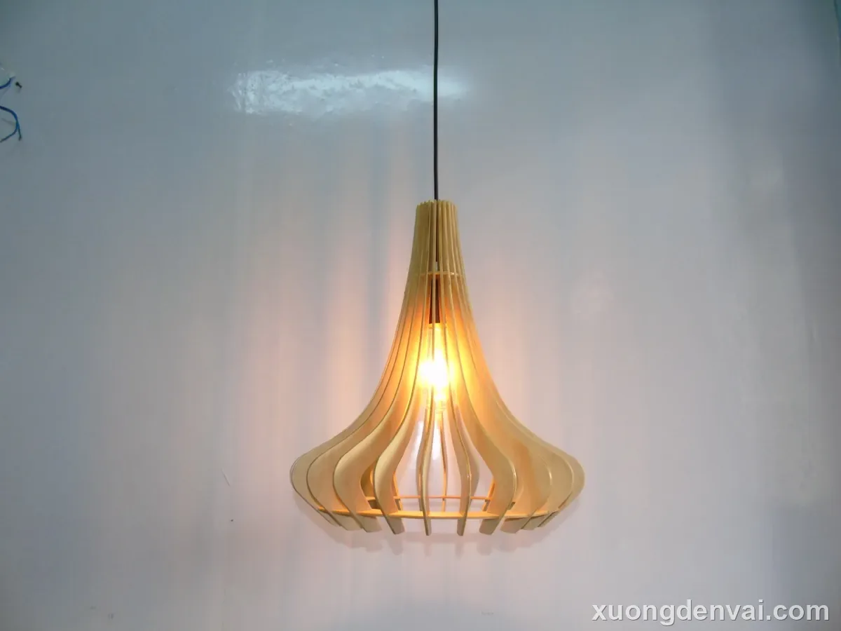 Đèn gỗ thả trần dáng loa kèn, các nan gỗ cong xòe rộng ở đáy và thu nhỏ dần lên phần cổ đèn, bóng đèn dây tóc treo lộ ở giữa