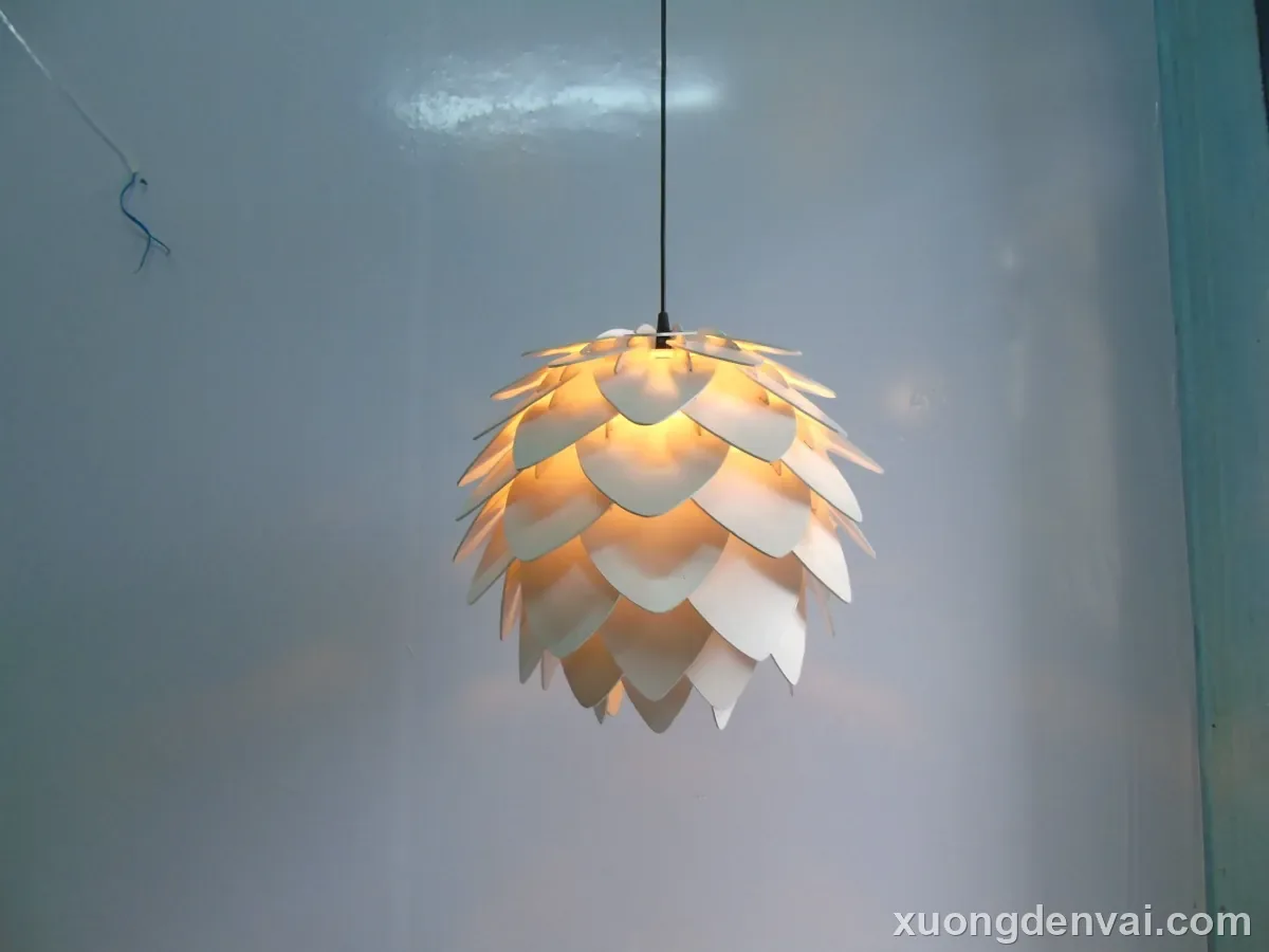 Đèn lồng gỗ thả trần dáng quả thông, các vảy gỗ mỏng xếp lớp từ đỉnh xuống đáy quanh bóng đèn
