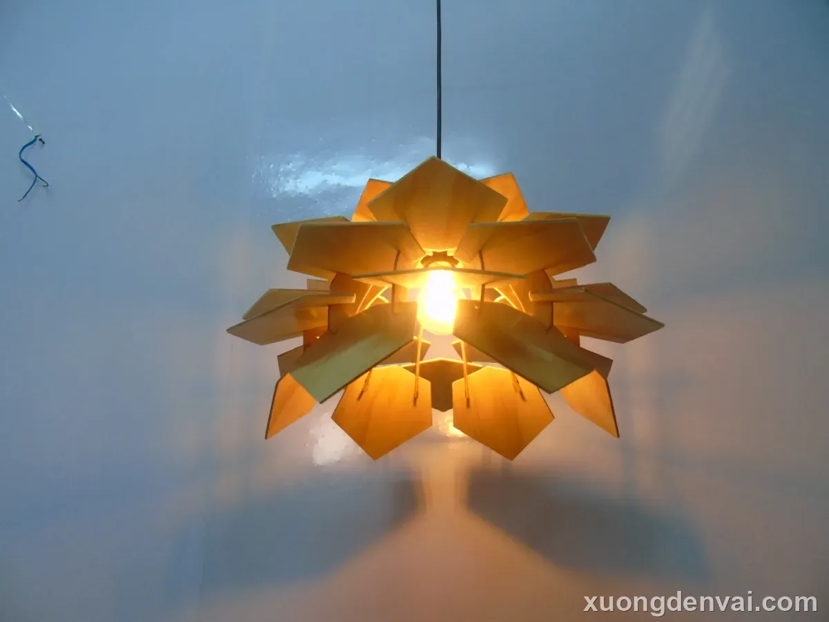 Đèn gỗ thả trần dáng hình sao nhiều cánh xòe, ghép từ nhiều mảnh gỗ đa giác chồng lớp quanh bóng đèn