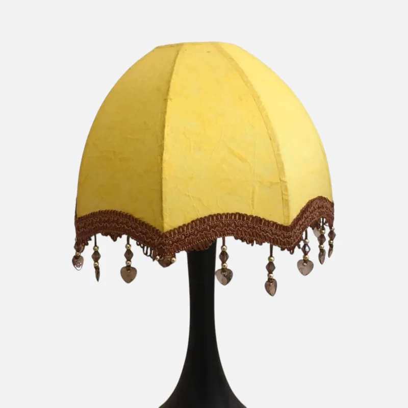 Đèn để bàn chao vòm tám múi vàng nghệ bề mặt nhăn thủ công, diềm ren nâu kết tua hạt, chân đèn đen thon